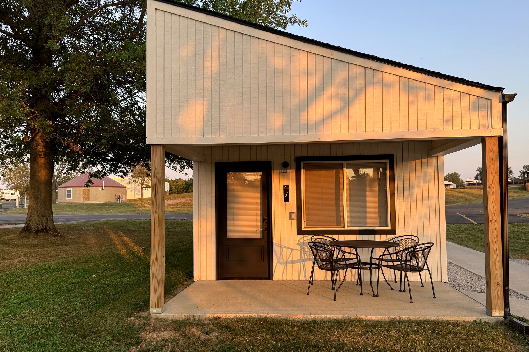 Modern cabin with covered porch and patio seating at golden hour